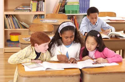 school children reading a book together